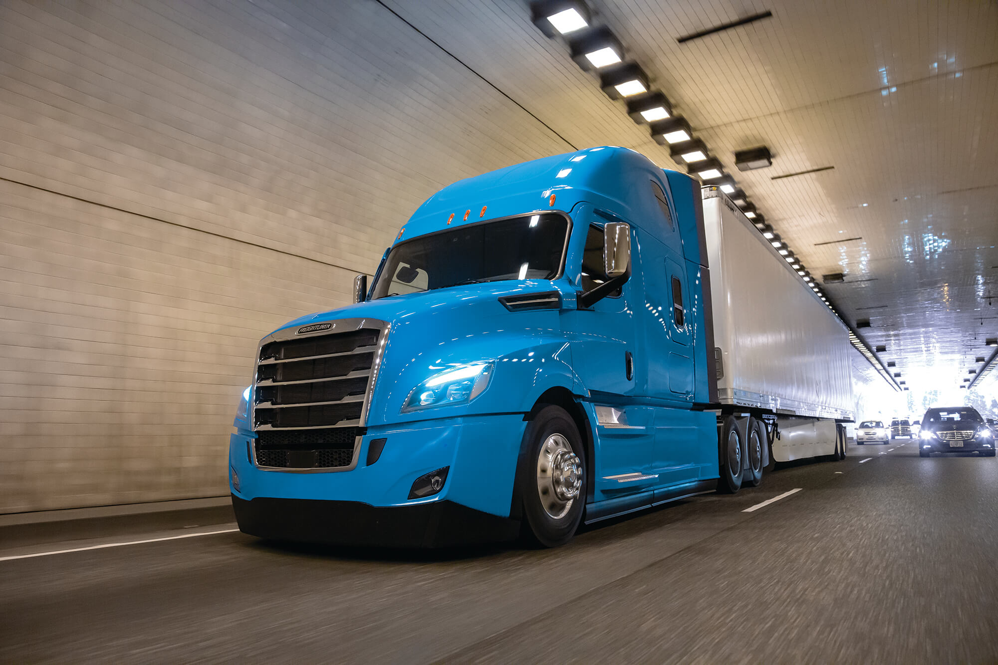 Blue Freightliner Cascadia driving through a tunnel